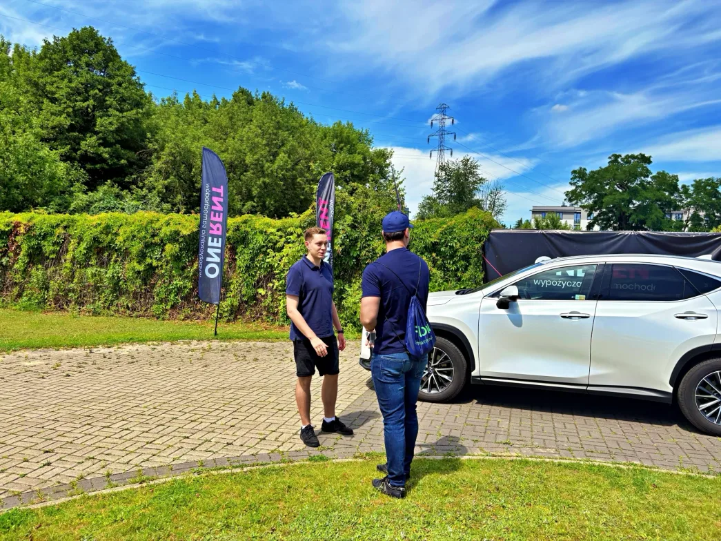 Lexus NX przekazywany kierowcy-partnerowy Flovi przez pracownika wypożyczalni One Rent.