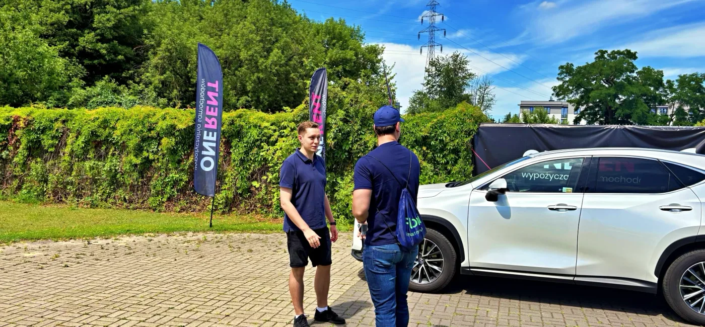 Lexus NX przekazywany kierowcy-partnerowy Flovi przez pracownika wypożyczalni One Rent.